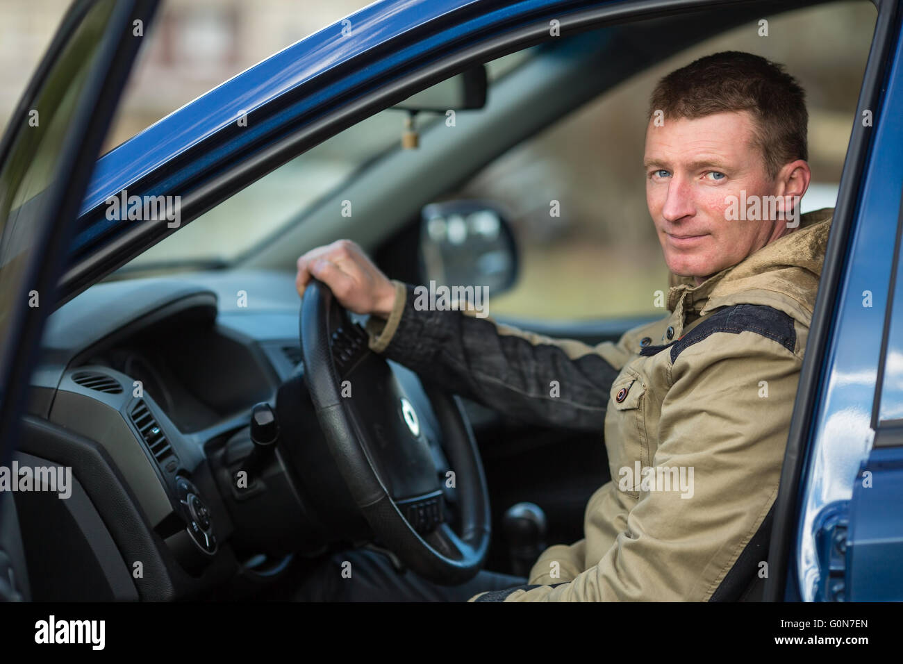 A young man sits behind the wheel of a car. Stock Photo