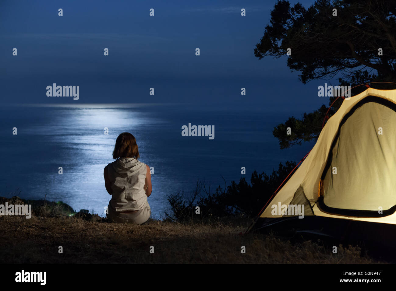 Alone woman near tent at night Stock Photo