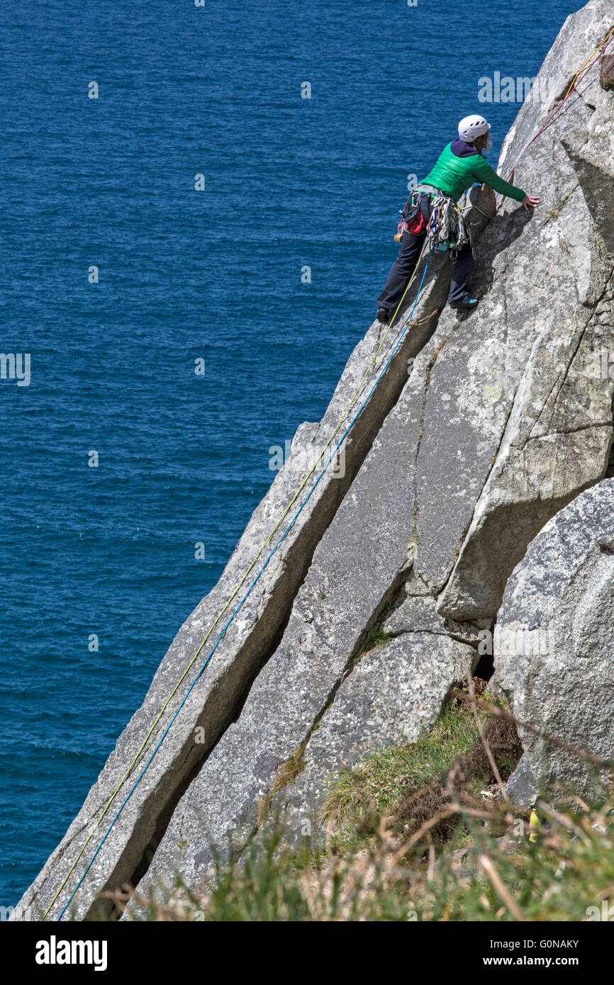 Lone, solo, female climber, leading a climb on the cliffs at Bosigran in Cornwall, England. Stock Photo