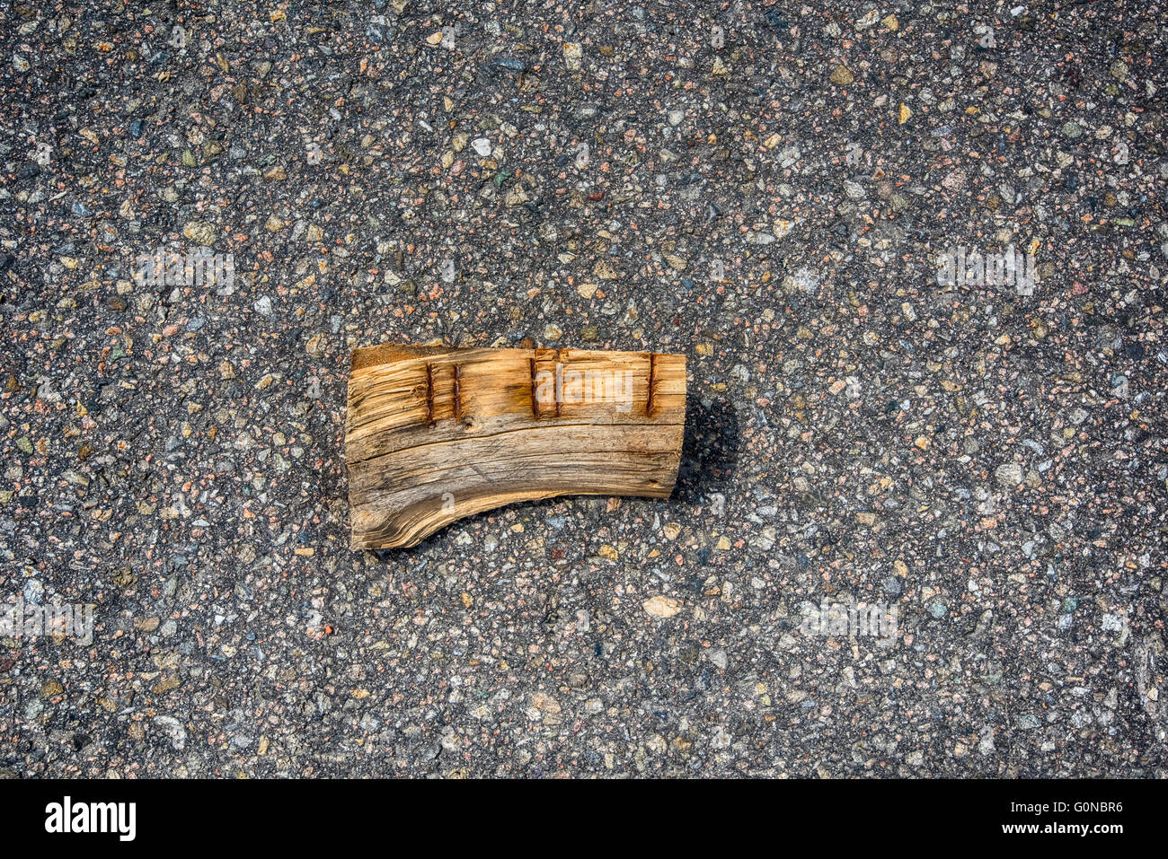 Broken rusty piece of wood on concrete asphalt floor Stock Photo