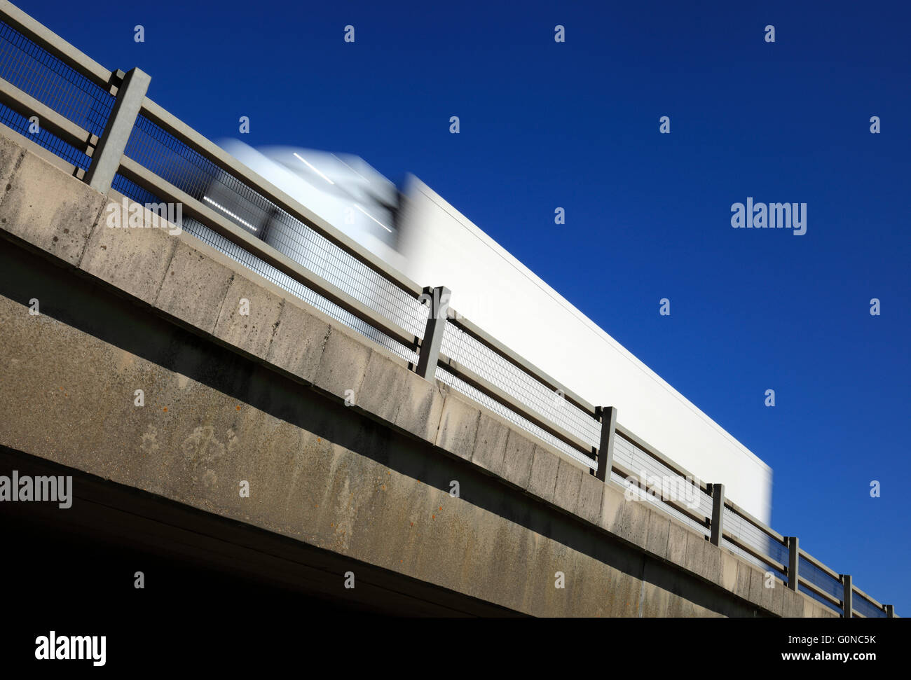 Heavy goods vehicle passing above on a flyover against a blue sky. Stock Photo
