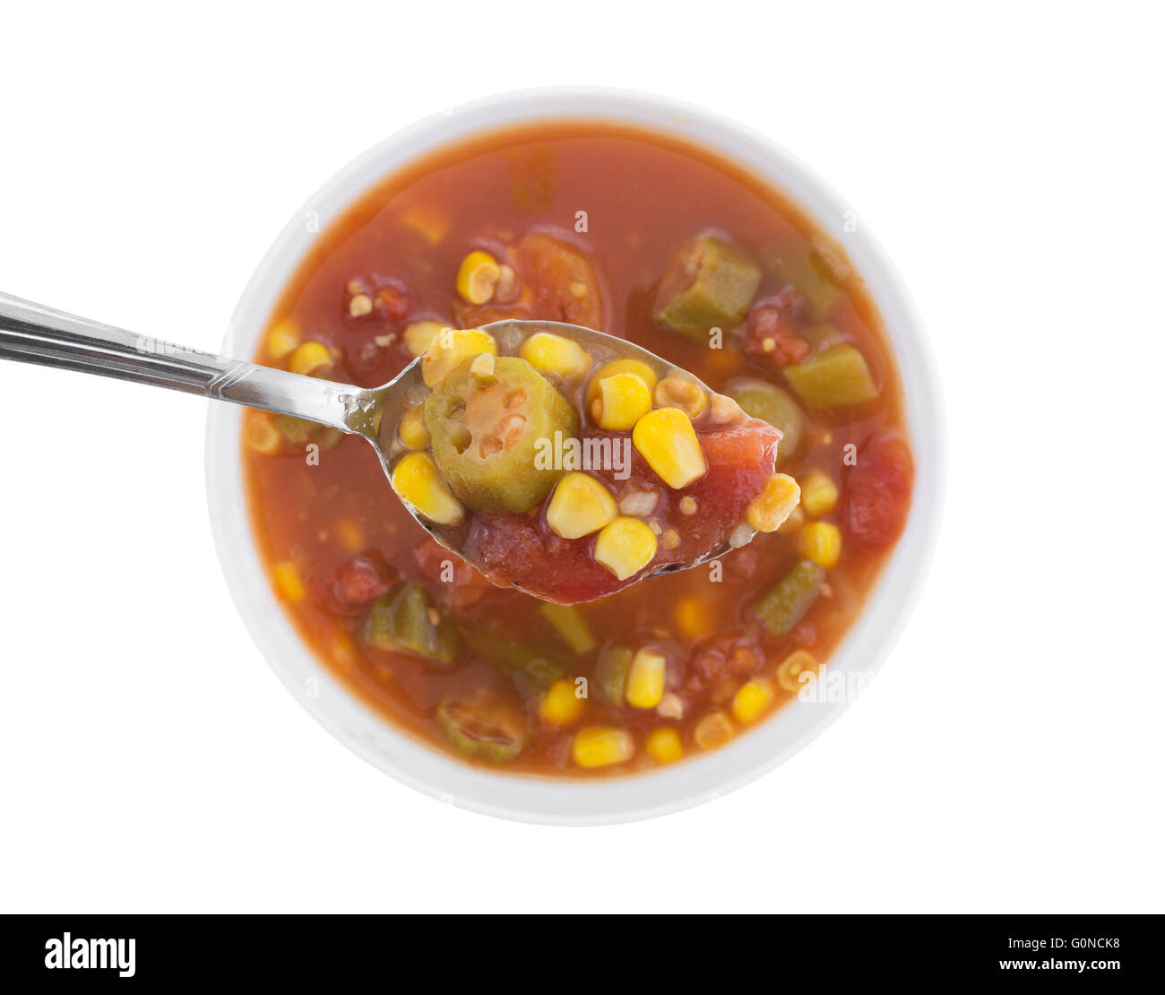 Top view of a spoonful of corn, okra and stewed tomatoes with the remainder of the vegetables in water with seasonings Stock Photo