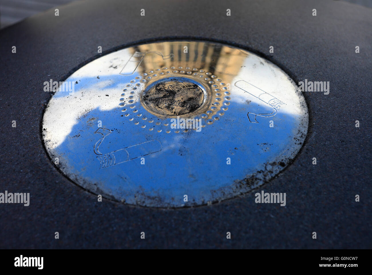 Ashtray outside with the reflection of a church and sky on silvery surface. Stock Photo