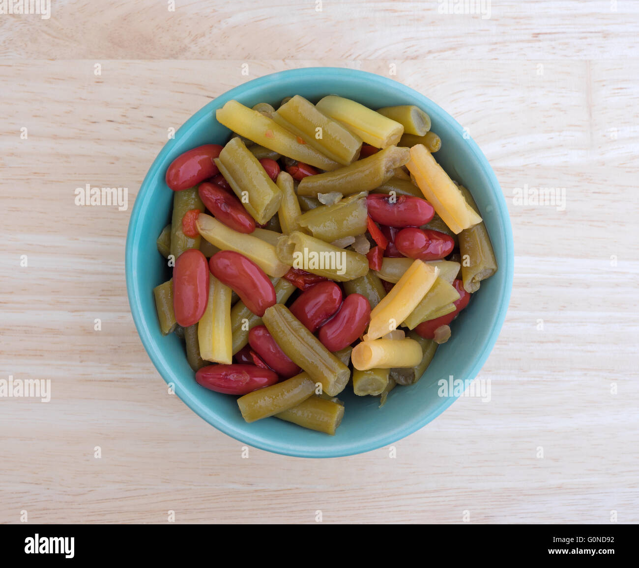 Top view of three bean salad in a small bowl atop a wood table top. Stock Photo