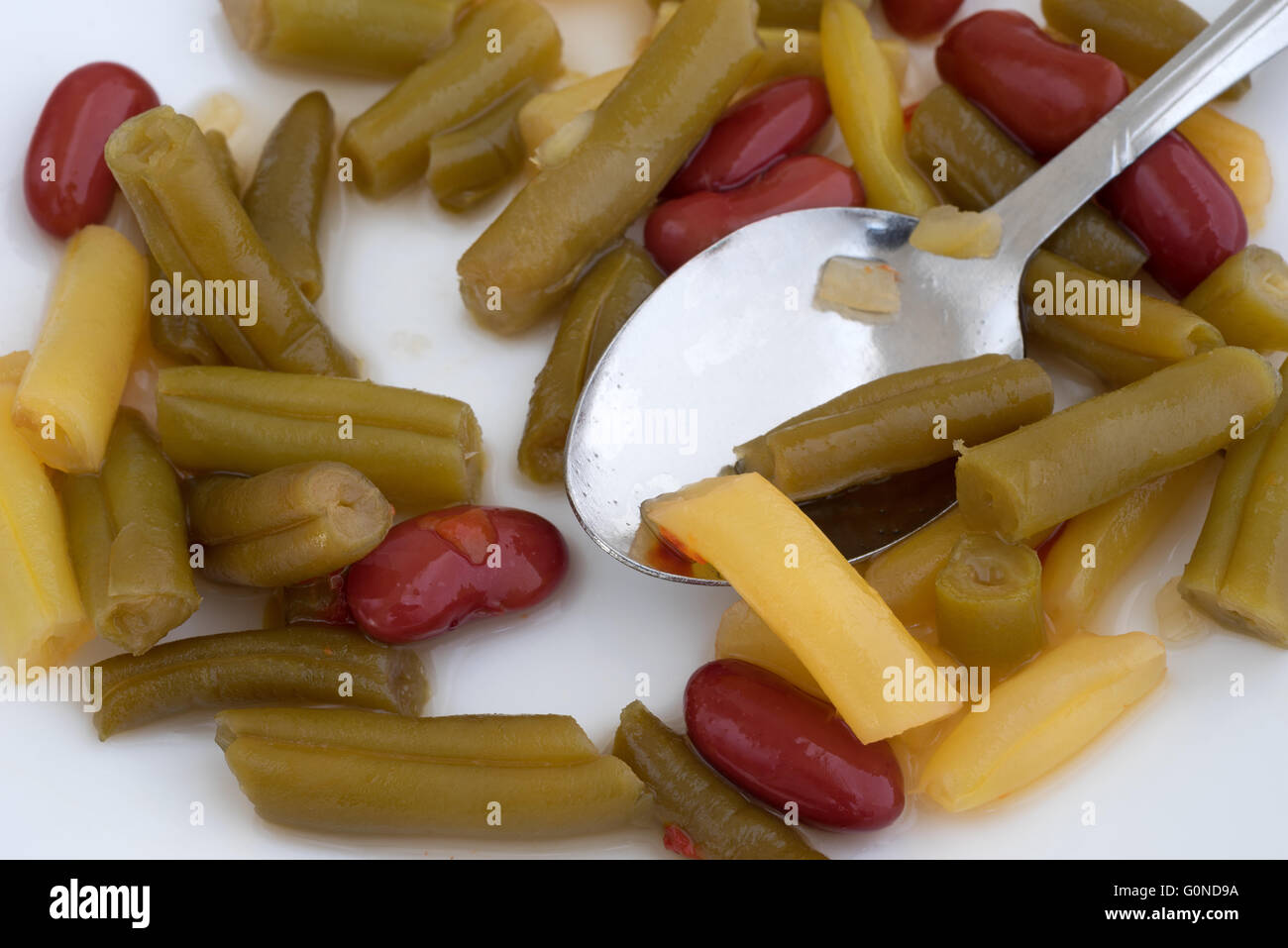 A very close view of three bean salad on a white plate with a spoon. Stock Photo