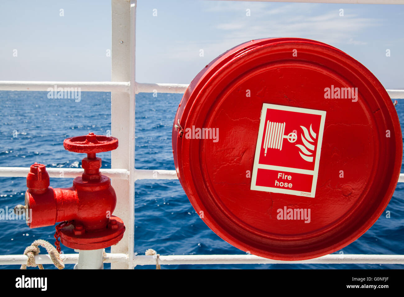 Red fire extinguisher with pipe connector on a boat Stock Photo