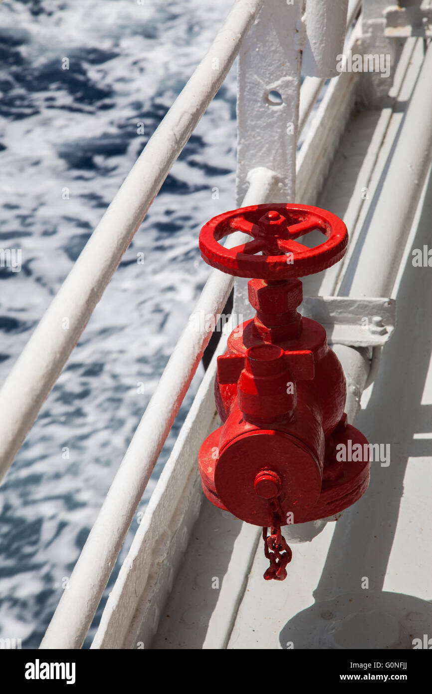 Red fire extinguisher with pipe connector on a boat Stock Photo