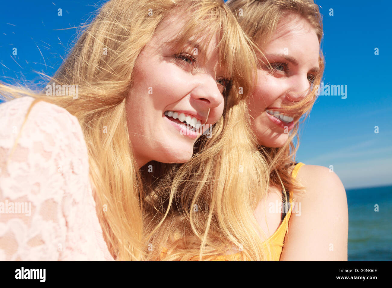 Two young women best friends blonde cheerful girls having fun outdoor wind blowing in hair. Summer happiness friendship concept. Stock Photo