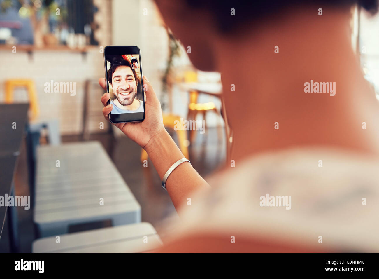 Man and woman talking to each other through a videochat on a mobile phone. Woman having a video call with man on her smart phone Stock Photo