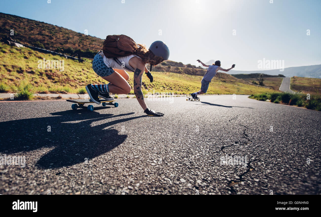 Young people skateboarding outdoors on the road. Young man and woman practicing skating on a rural road. Stock Photo