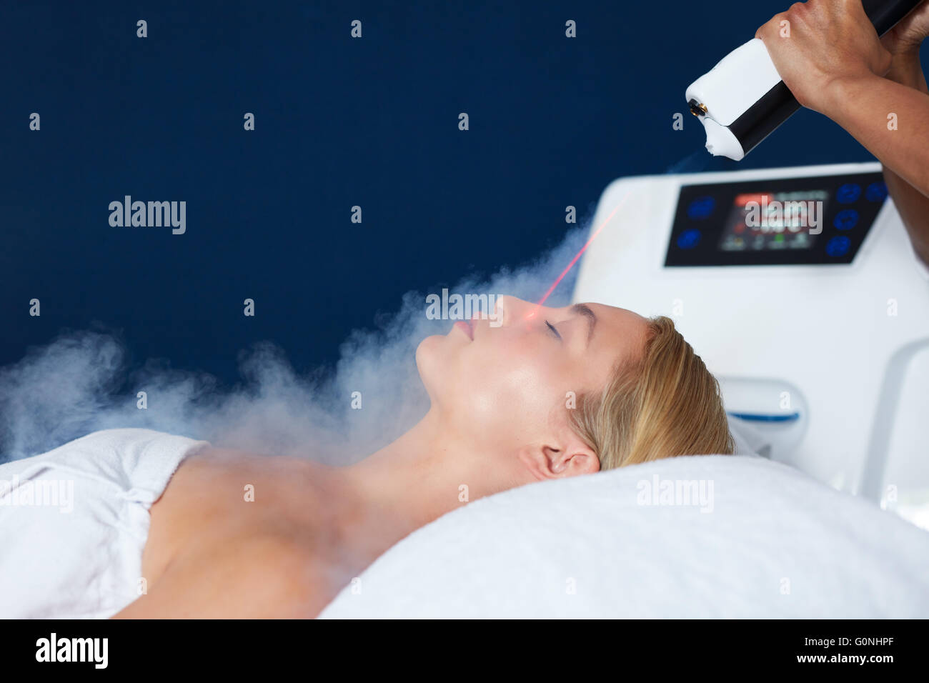 Beautiful young woman getting local cryotherapy therapy in cosmetology clinic. Beautician applying cold nitrogen vapors to the f Stock Photo