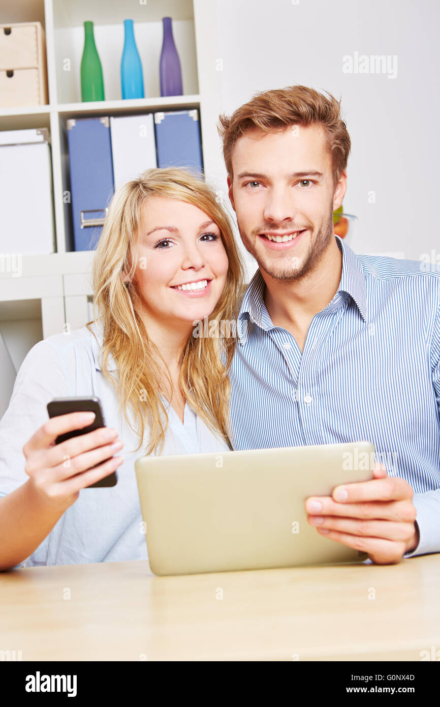 Happy couple with smartphone and tablet computer sitting in the living room Stock Photo