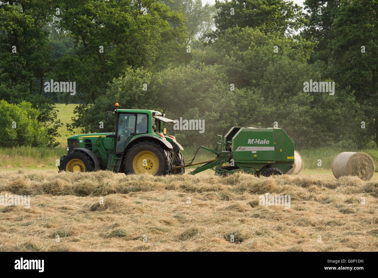 Silage making - Farm tractor pulling a round baler is working in a field at Great Ouseburn, North Yorkshire, England. Stock Photo