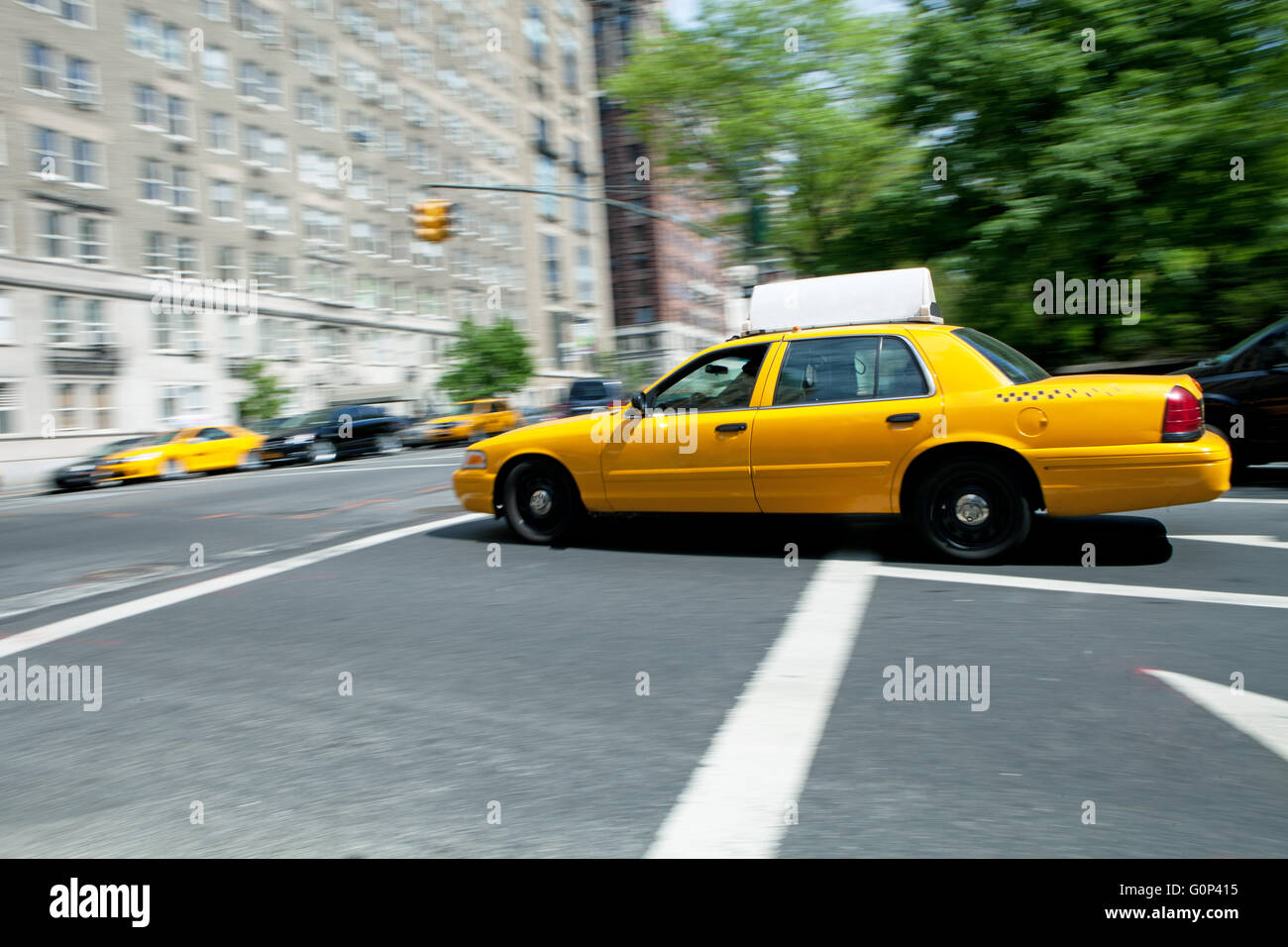 Yellow NYC taxi cab speeding by during daytime.  Slow shutter speed panning technique used for motion blur. Stock Photo