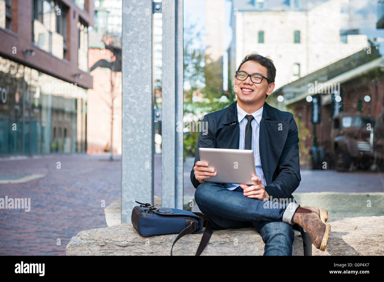 Young smiling asian business man holding a digital tablet sitting ...