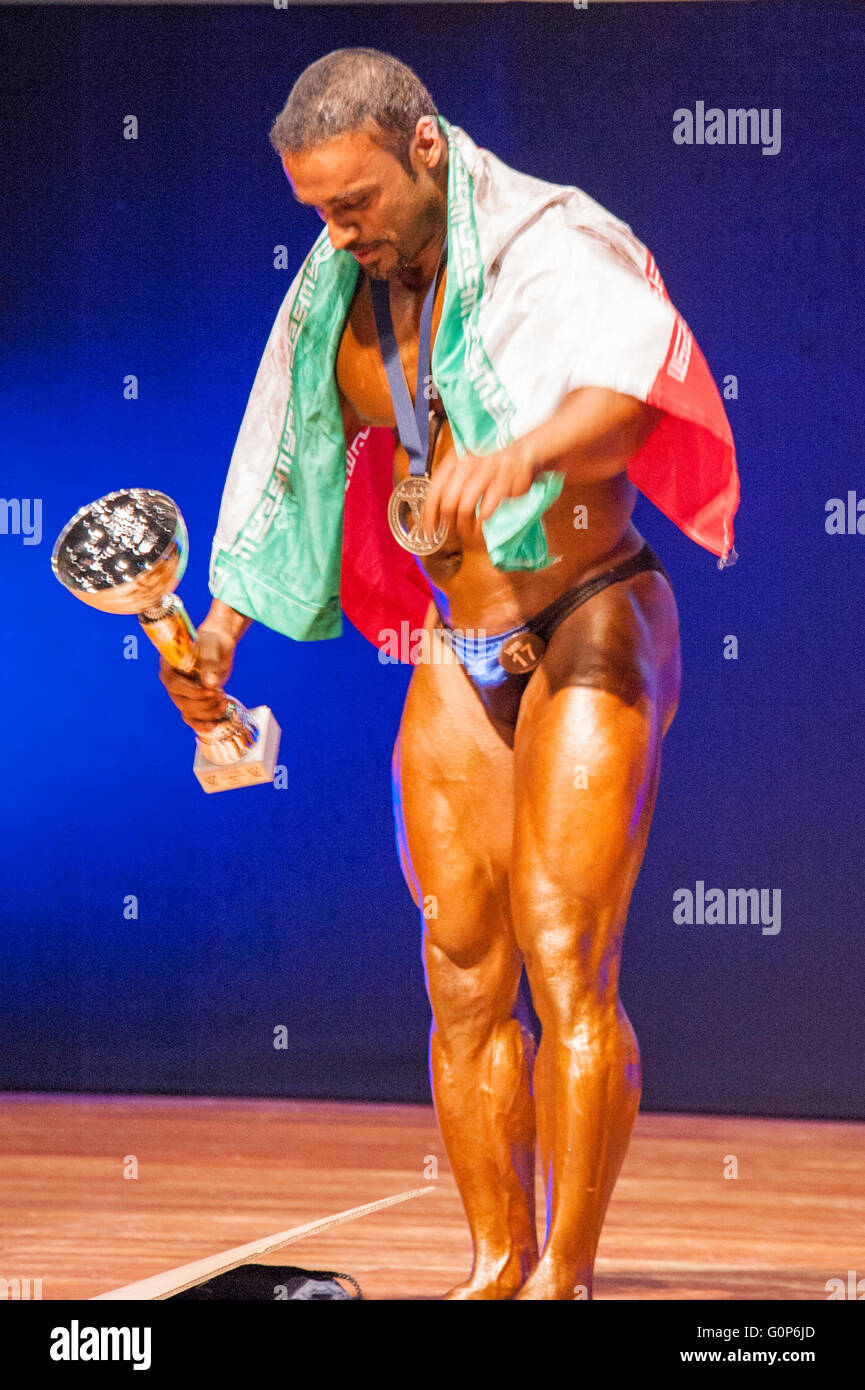 MAASTRICHT, THE NETHERLANDS - OCTOBER 25, 2015: Male bodybuilder celebrates his victory on stage with his national flag of Iran  Stock Photo