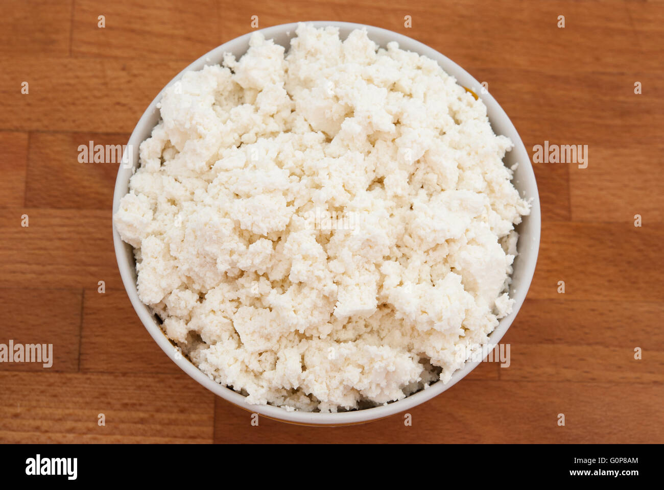 Cottage cheese (curd cheese, quark, anari) in a bowl with a wood background closeup Stock Photo