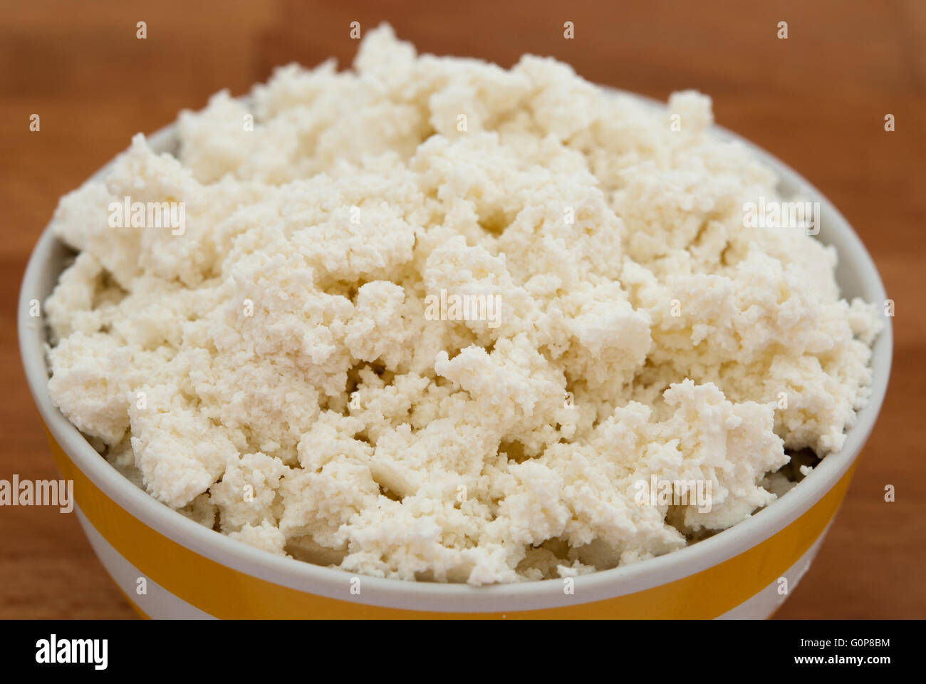 Cottage cheese (curd cheese, quark, anari) in a bowl with a wood background closeup Stock Photo