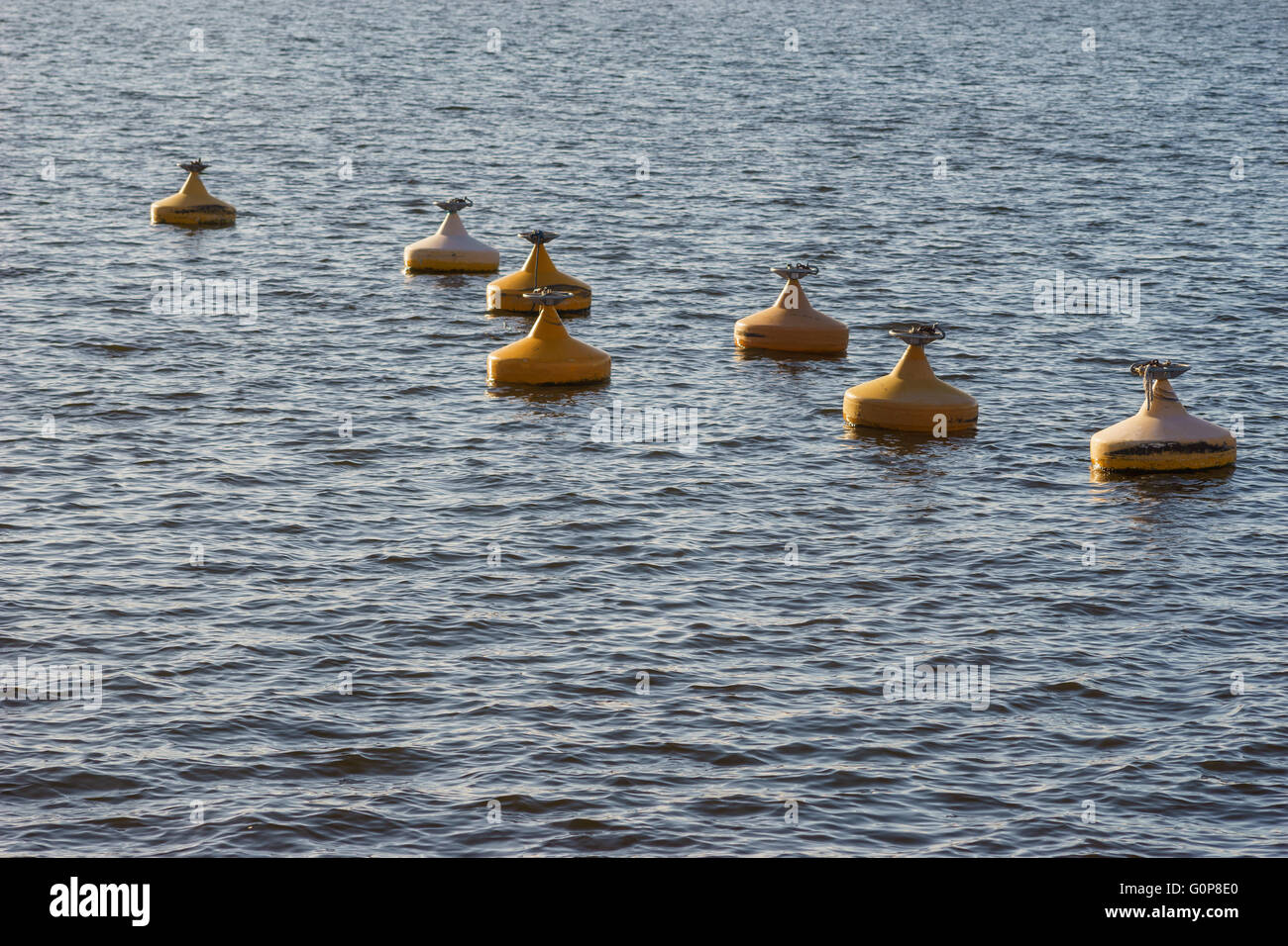 Many of yellow metal buoys floating in sea water Stock Photo