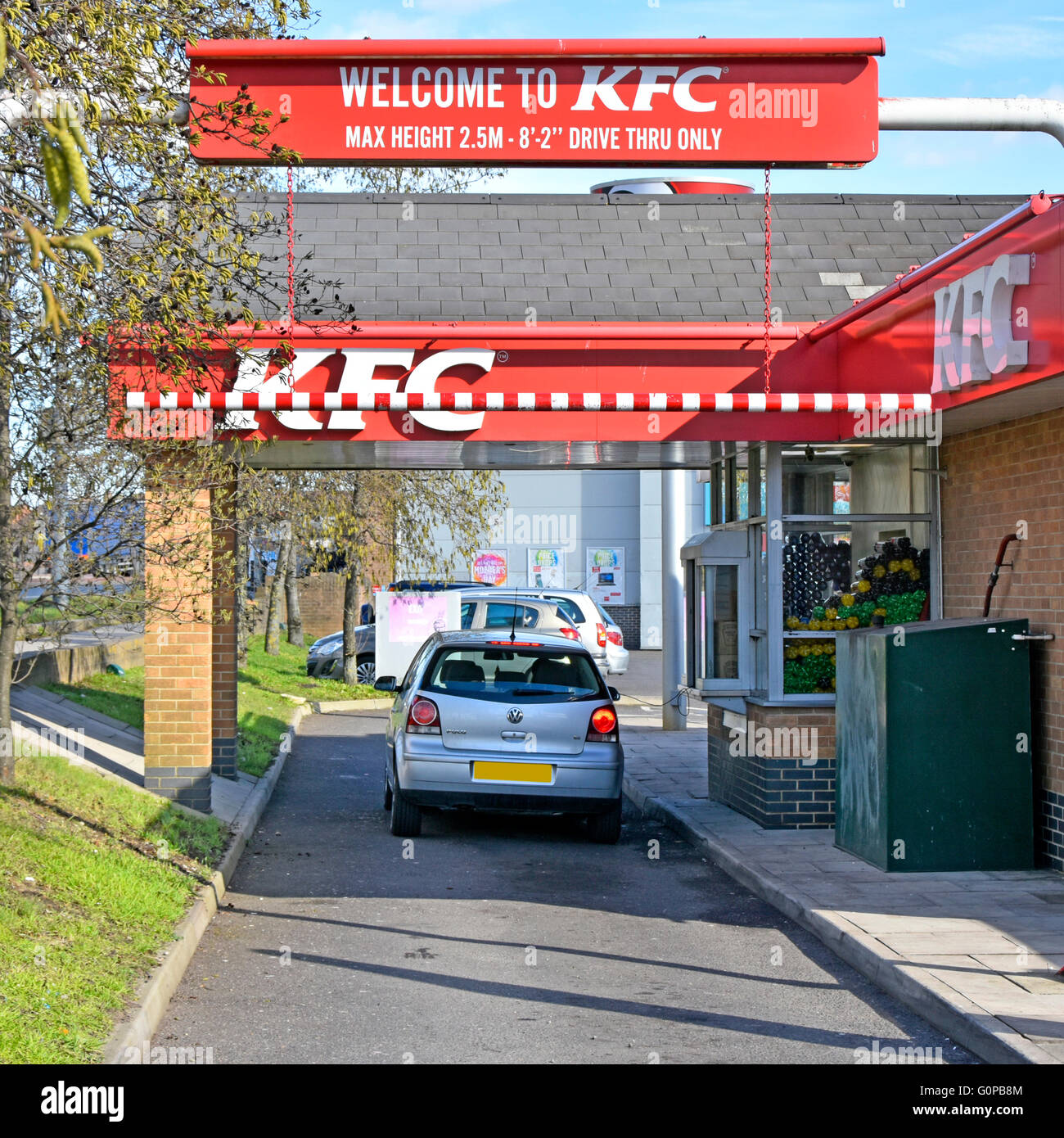 KFC drive through lane with customer in car ordering & collecting at window East London England UK (obscured number plate) Stock Photo
