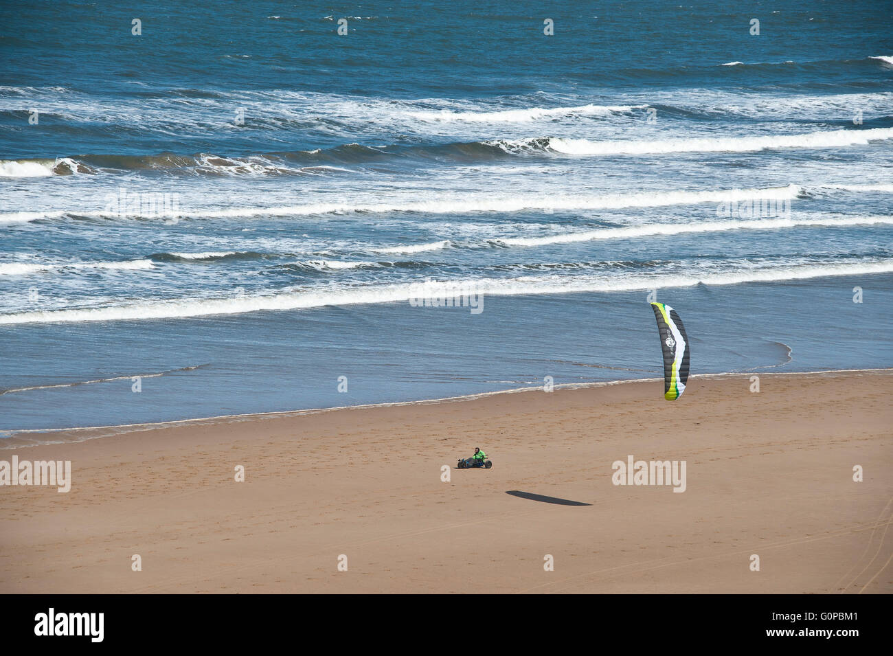 man riding a beach buggy at speed with a power kite on saltburn beach using wind energy on sand