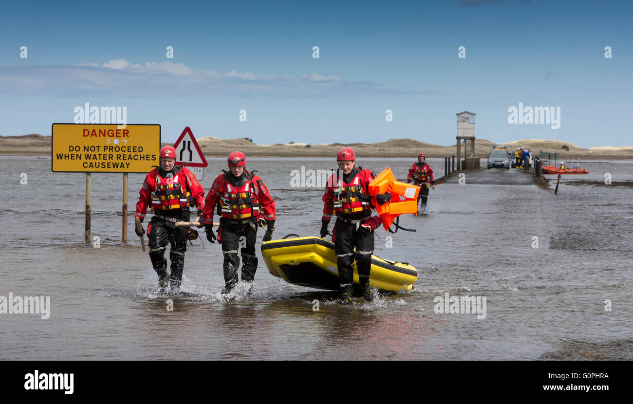 Holy Island, Lindisfarne, Northumberland, UK. 3rd May, 2016. Fire Rescue officers wade ashore though ankle deep water after a panicked motorist, attempting to cross before low tide cleared the Holy Island Causeway, caused a high scale alert involving five emergency services Credit:  Neil McAllister/Alamy Live News Stock Photo