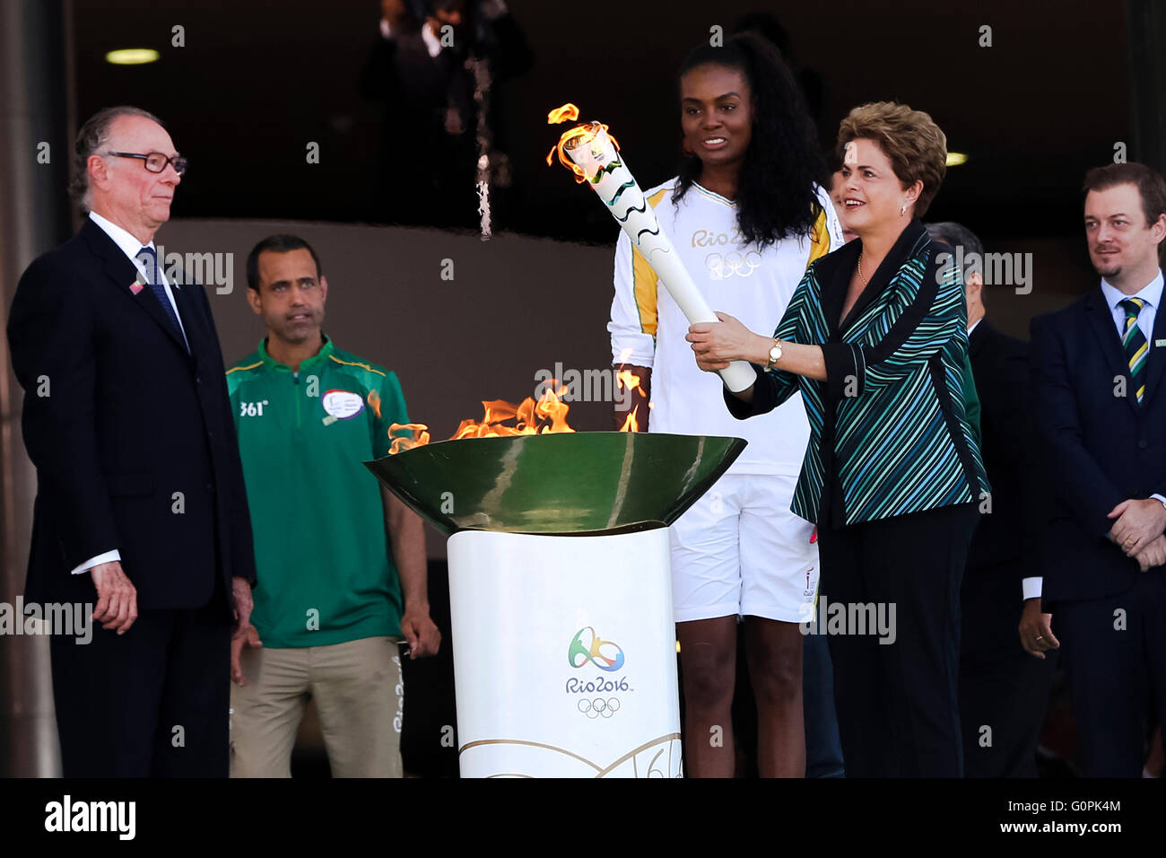 Brazilian President Dilma Rousseff lights the Olympic flame as Brazilian volleyball player Fabiana Claudino looks on during the lighting ceremony at Planalto presidential palace May 3, 2016 in Brasilia, Brazil. The torch relay will begin a three month journey around Brazil before arriving for the Rio de Janeiro Olympics in August. Stock Photo