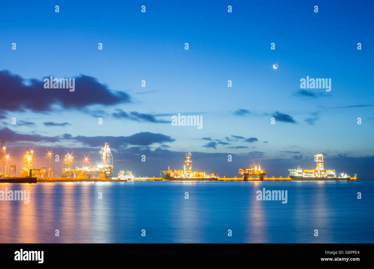 Rigs at dawn, Las Palmas, Gran Canaria, Canary Islands, Spain, 4th May 2016. Weather: The Moon rises over  Oil rigs, drilling ships and accomodation platform in pre dawn light in Las Palmas port on a glorious Wednesday morning on Gran Canaria. PICTURED: Las Palmas port is used by a number of oil companies for repairs, resupplying, and in the the case of some of the rigs/platforms in these images, for mothballing rigs for long periods due to the fall in oil prices and over supply of crude oil. Credit:  Alan Dawson News/Alamy Live News Stock Photo