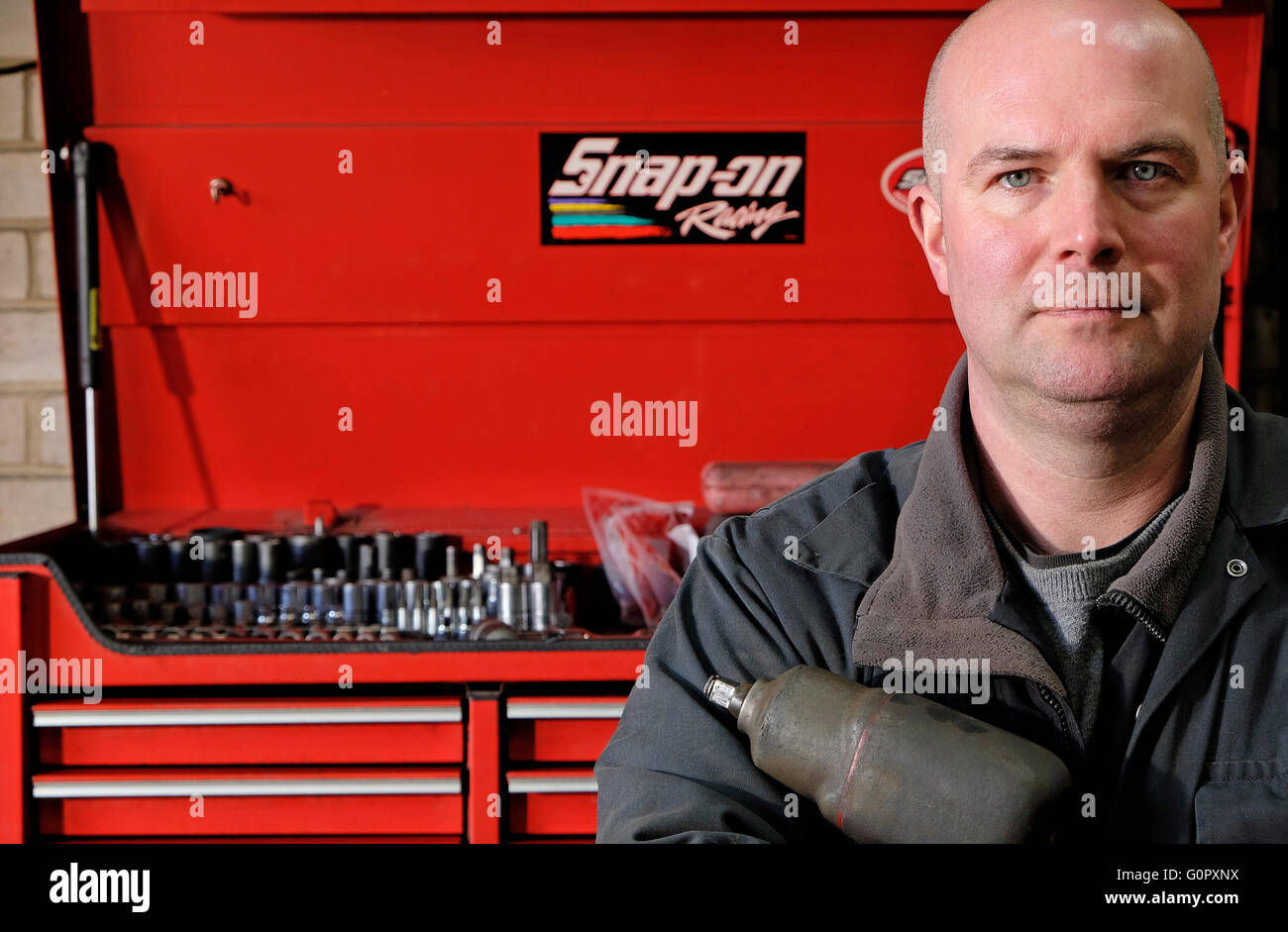 male motor mechanic standing in front of red tool box Stock Photo
