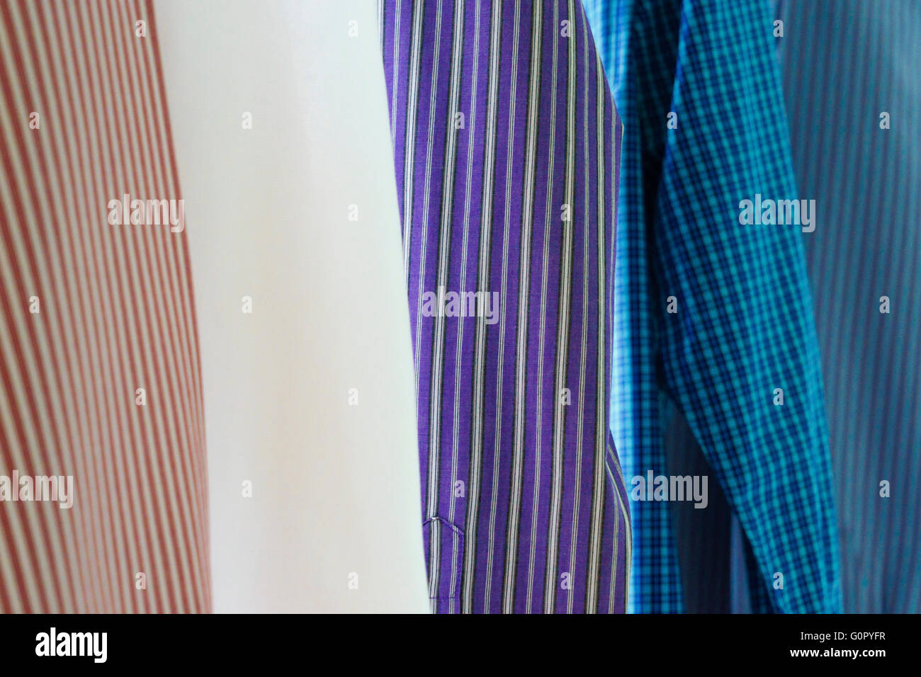 Colourful striped and patterned mens shirts hanging up after being ironed. Stock Photo