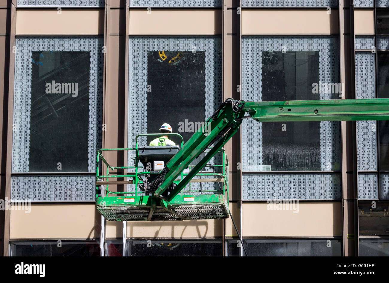 Window cleaner on green hydraulic lift platform in Soho in New York City Stock Photo