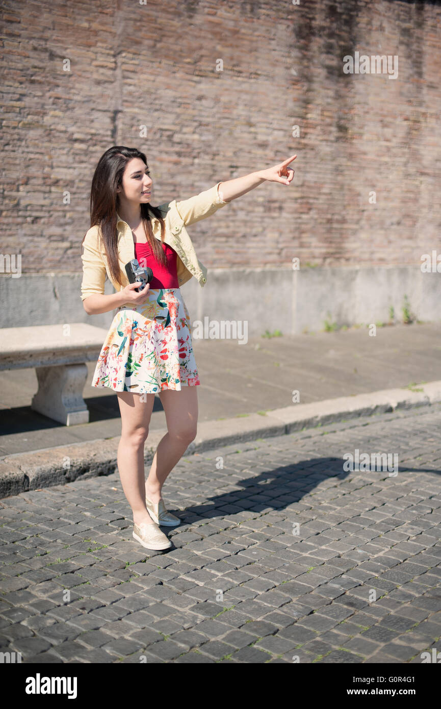 Young woman tourist with vintage camera pointing out outdoor Stock Photo