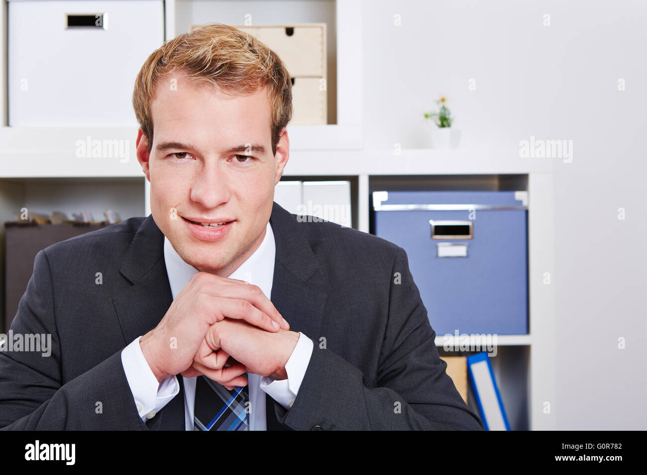 Smiling attractive business man sitting in his office Stock Photo - Alamy