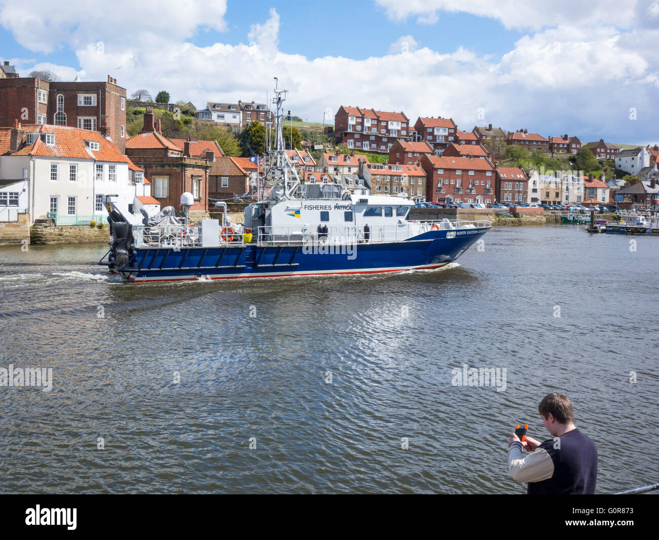 North Eastern Guardian lll fisheries patrol vessel entering Whitby harbour passing a boy fishing with a hand line. Stock Photo