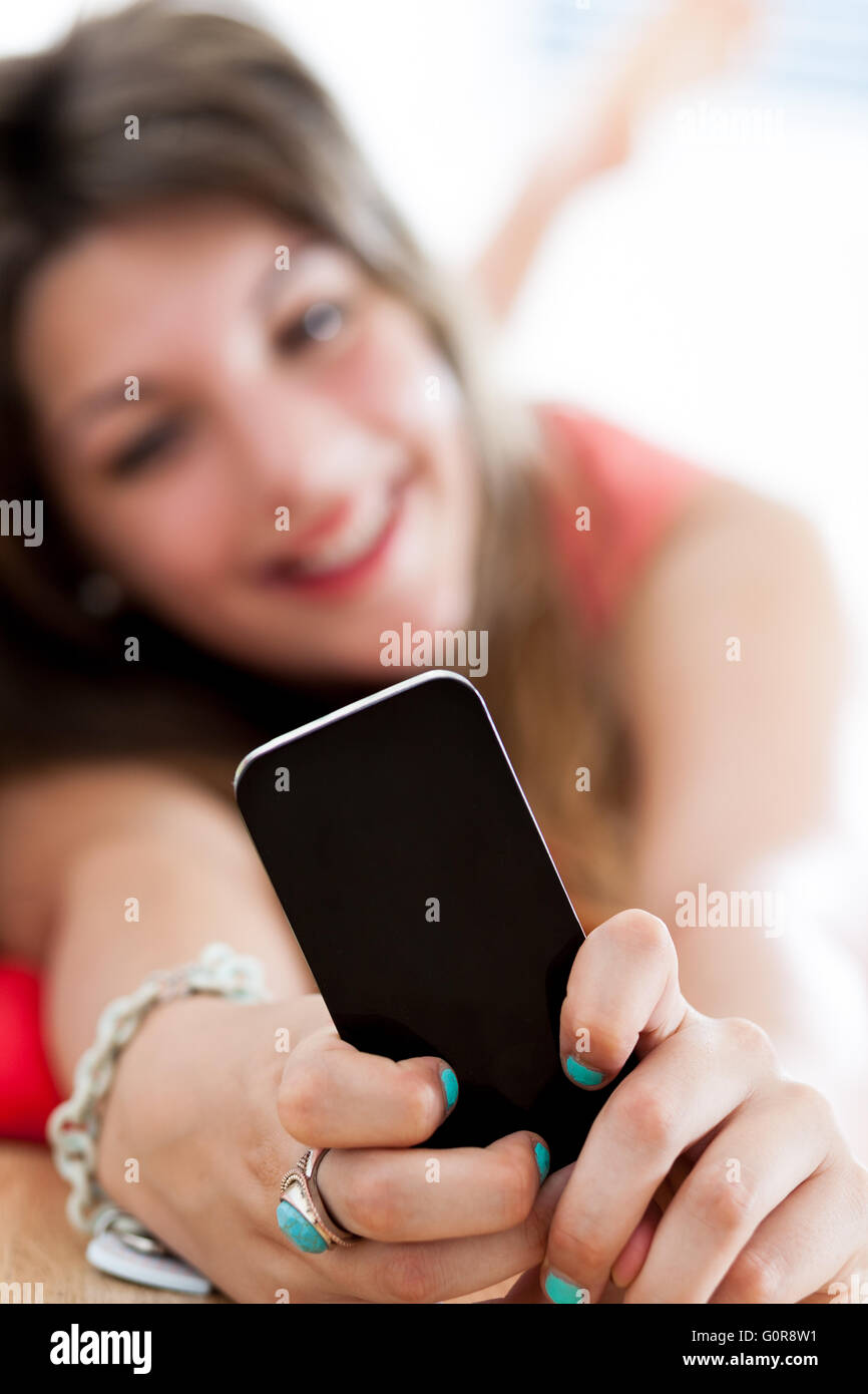 smiling woman looking at something in her smartphone at home Stock Photo