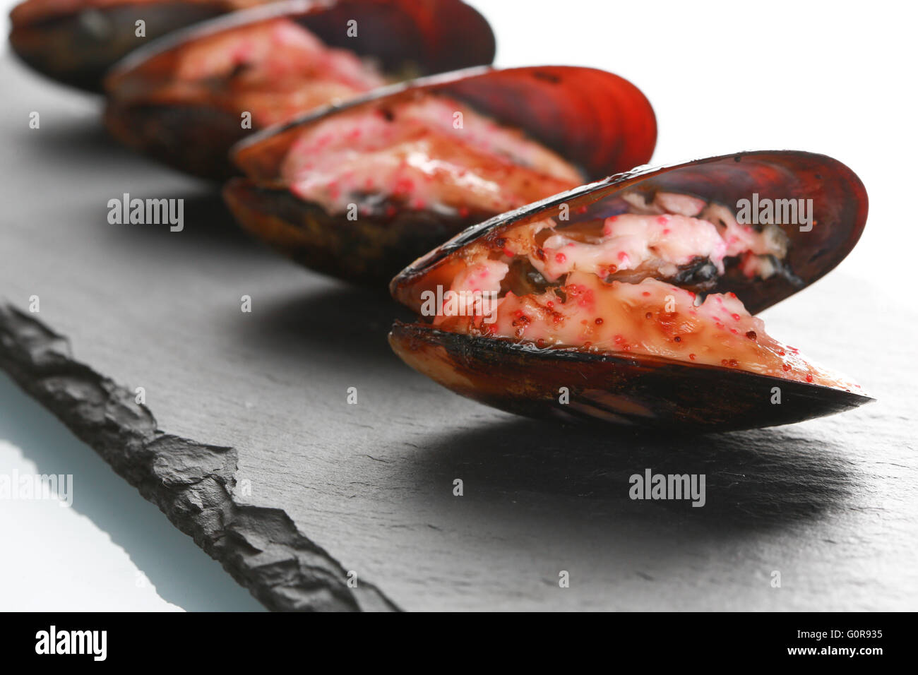 mussels in their shell on a black slate plate Stock Photo