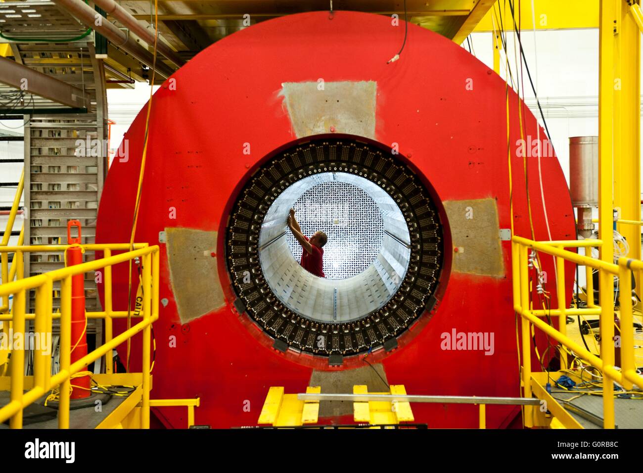 Scientist John Leckey works on one of a series of detector systems being installed in the Hall D Superconducting Solenoid at the Thomas Jefferson National Accelerator Facility in Newport News, Virginia. The solenoid and detectors will provide information on the particles being tracked during experiments. The magnet is approximately 200 inches long and weighs approximately 300 tons. Stock Photo