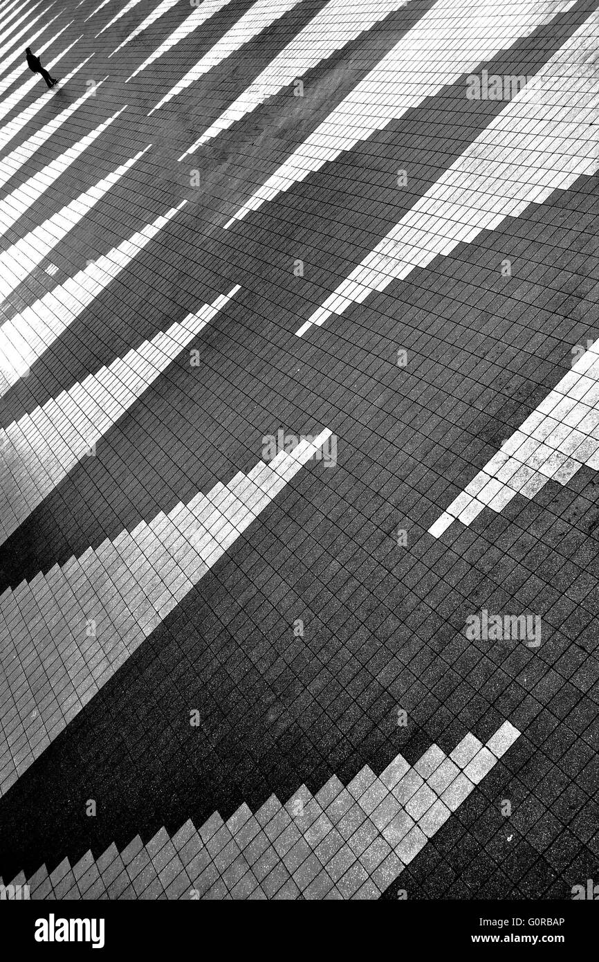 Lonely man is going away on empty square with zigzag pattern. Black and white photo Stock Photo