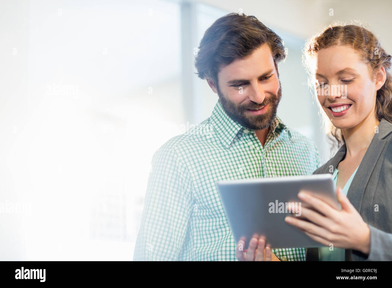Businessman and businesswoman discuss using digital tablet Stock Photo