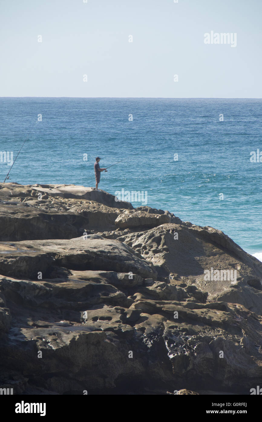 A man fishing from the cliffs at Bronte Beach, Sydney. Stock Photo