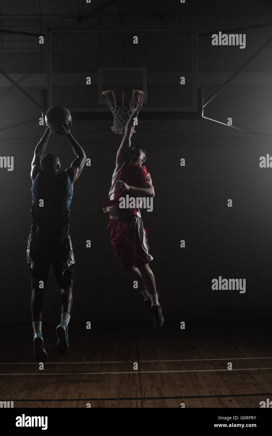 Basketball player shooting a basketball with a defender Stock Photo - Alamy