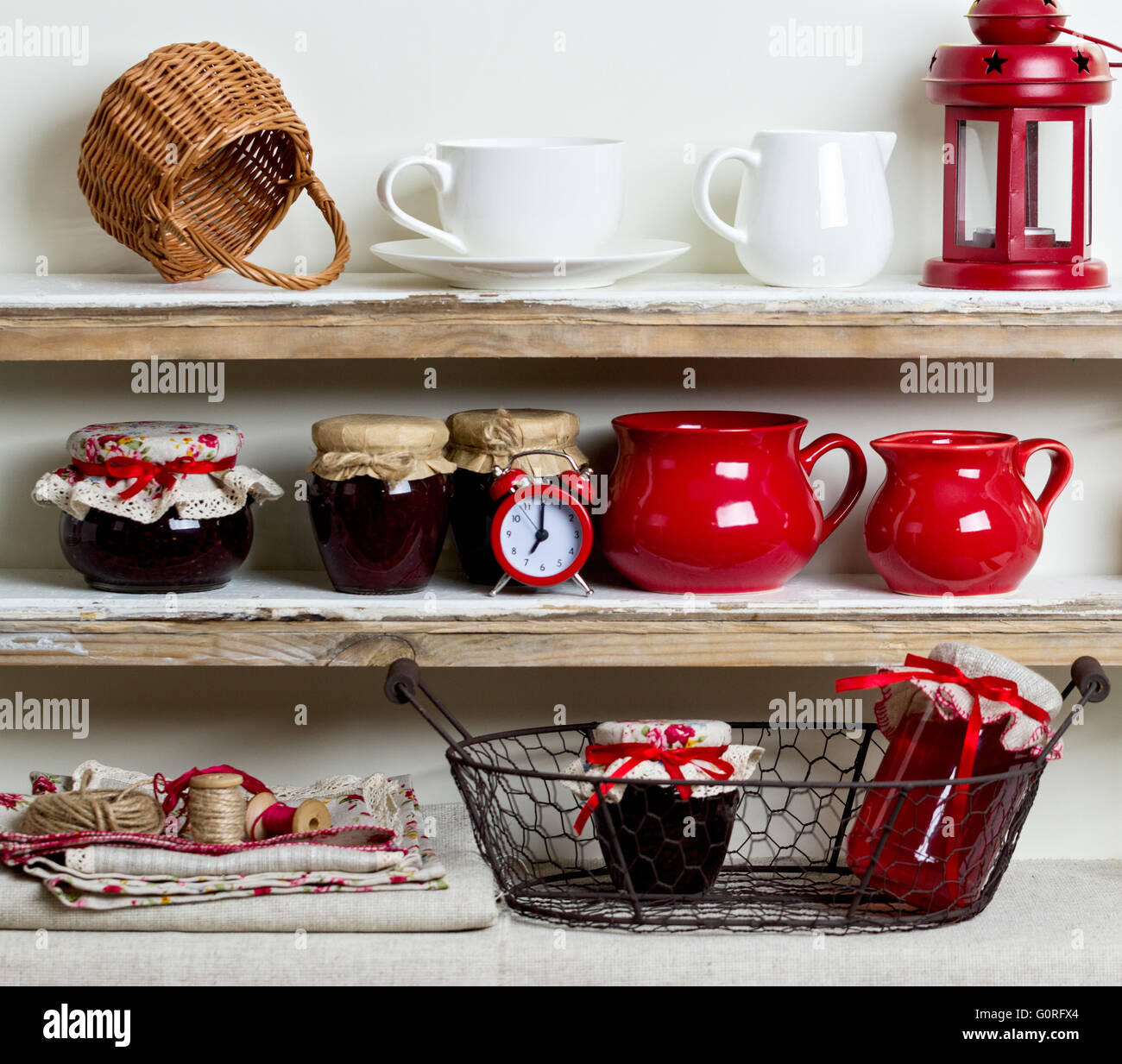 A rustic style. Ceramic tableware and kitchenware in red on the shelves ...
