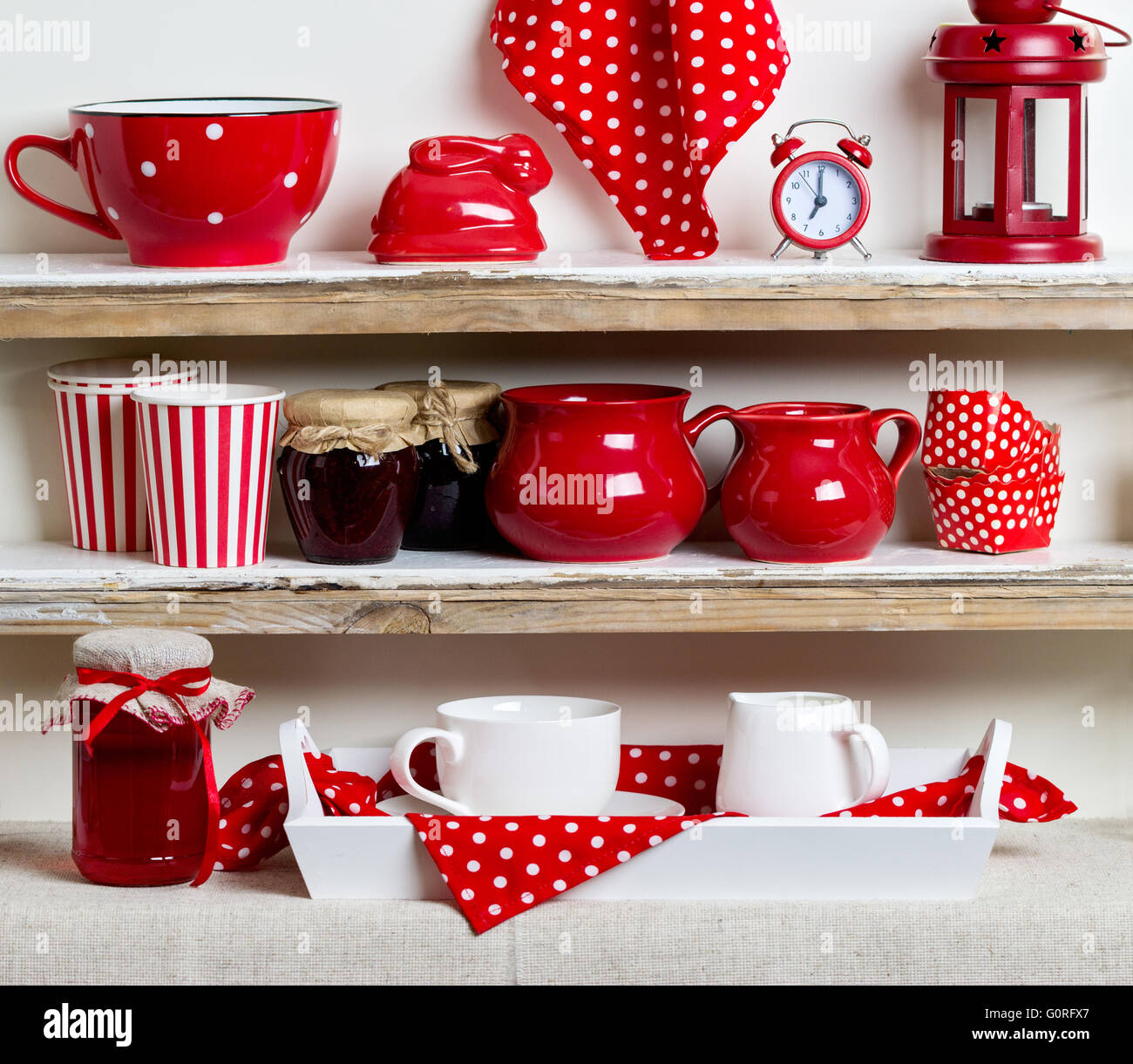A rustic style. Ceramic tableware and kitchenware in red on the shelves ...