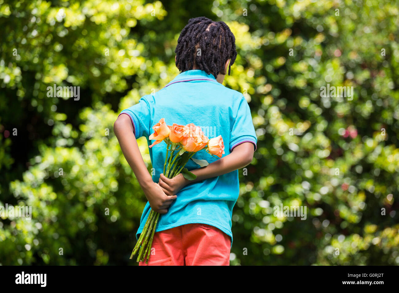 A kid hiding bouquet behind back Stock Photo