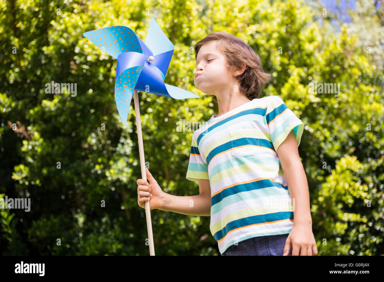 A little boy is blowing on pinwheel Stock Photo