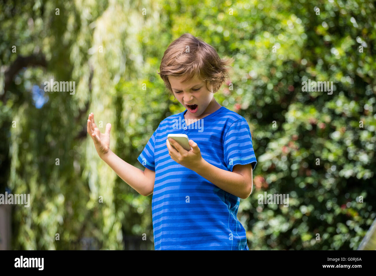 A little boy is angry with his mobile phone Stock Photo