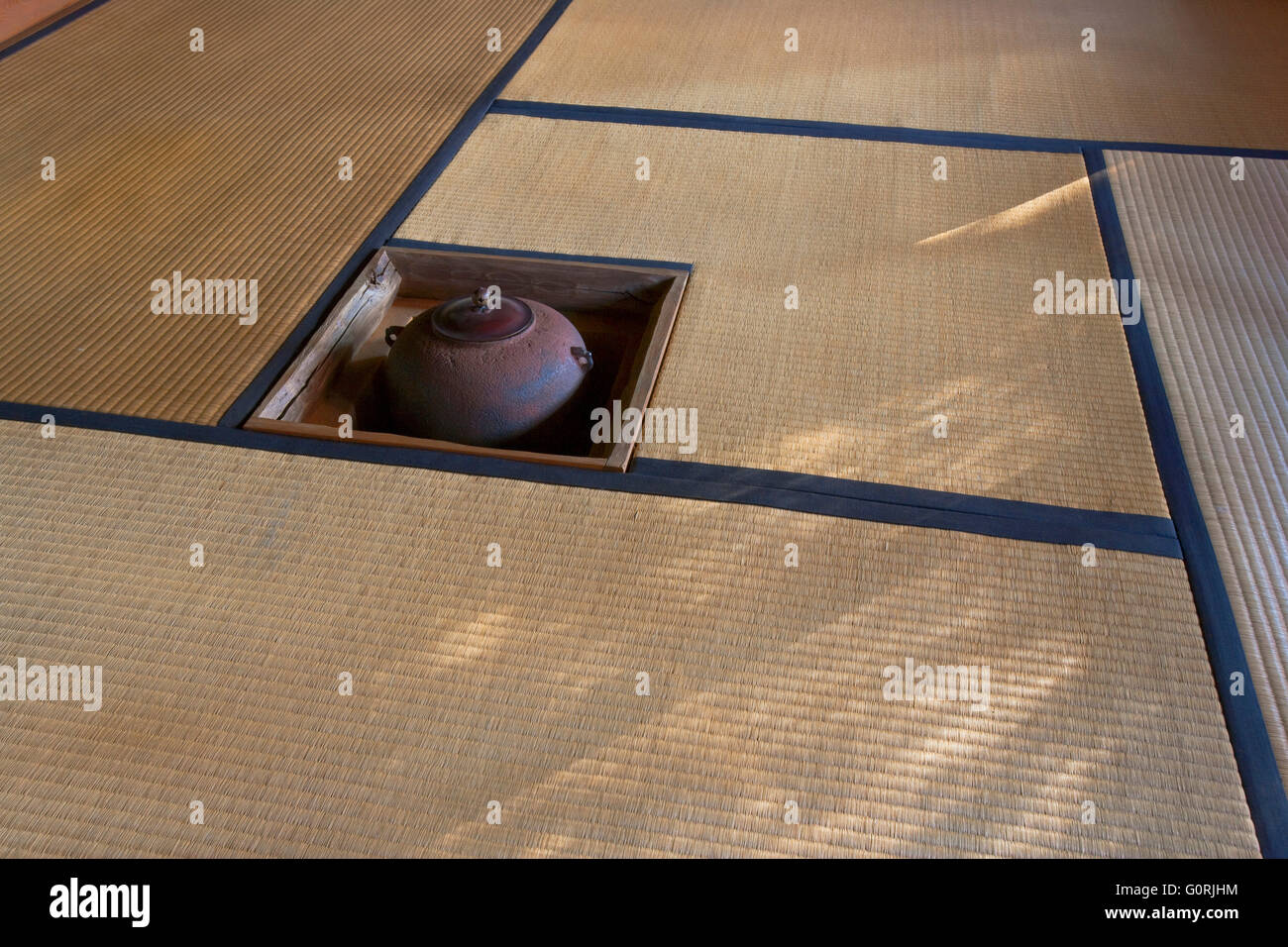A naturally-lit interior view shows the spartan simplicity of a Japanese tea-room with tatami mat floor and traditional irori hearth at Daiho-in, a sub-temple inside Myoshin-ji, which is a Zen Buddhist temple complex in Kyoto, Japan. Stock Photo