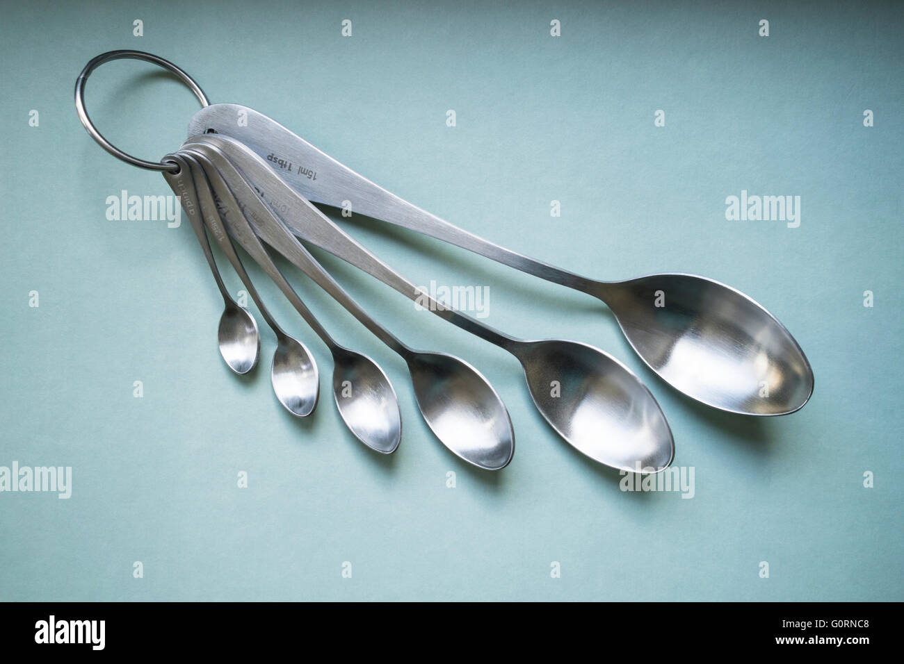 https://c8.alamy.com/comp/G0RNC8/a-set-of-brushed-stainless-steel-measuring-spoons-on-a-green-background-G0RNC8.jpg