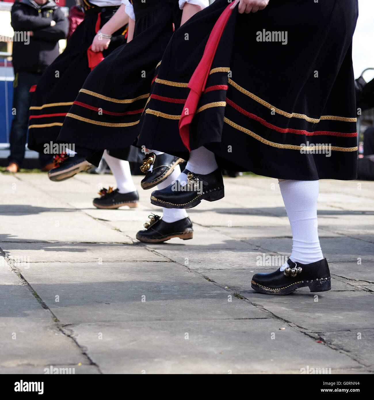 Feet of a morris dancing troop showing clogs and flowing dresses on a Yorkshire stone flagged pavement. Stock Photo