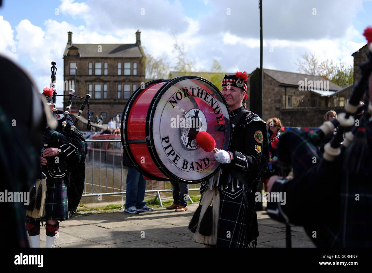 Northenden pipe band, dressed in kilts and uniform, with a drummer in action outside near bagpipes. Stock Photo